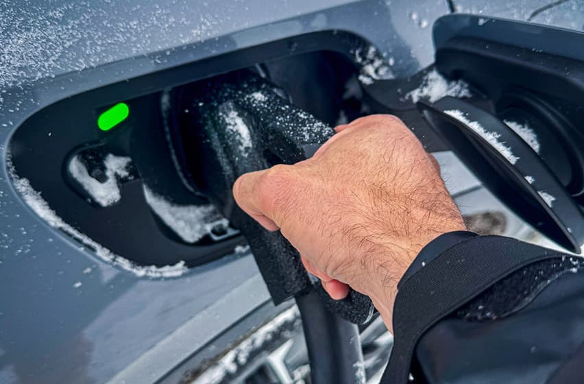 Hand charging EV cable closeup winter