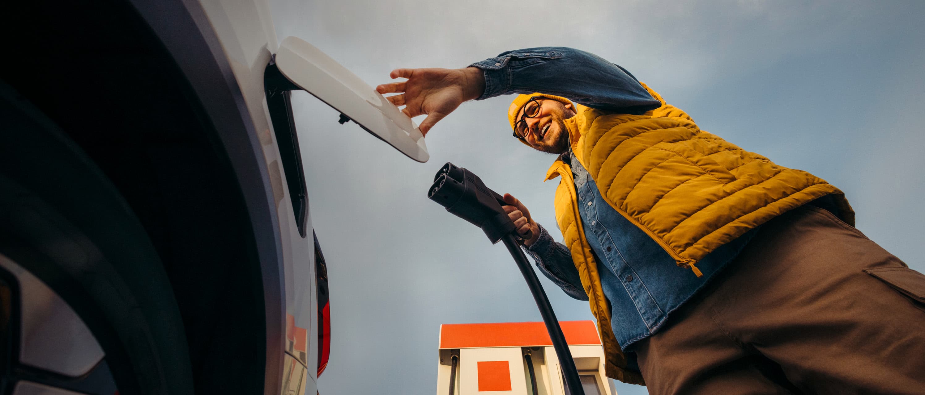 Man charging EV from the ground pov landscape